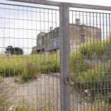 La struttura � circondata da una grande e alta cancellata in metallo chiusa da un grosso lucchetto e sorge solitaria tra l�erba alta e migliaia di gialle margherite